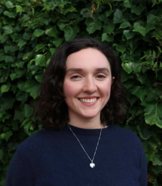A headshot of Isabella Villareal taken against a green leafy background