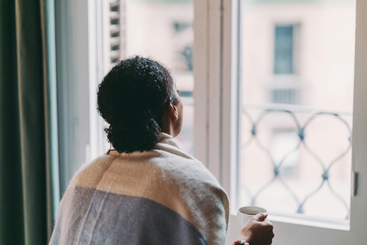 Woman looking out a window, facing away from the camera