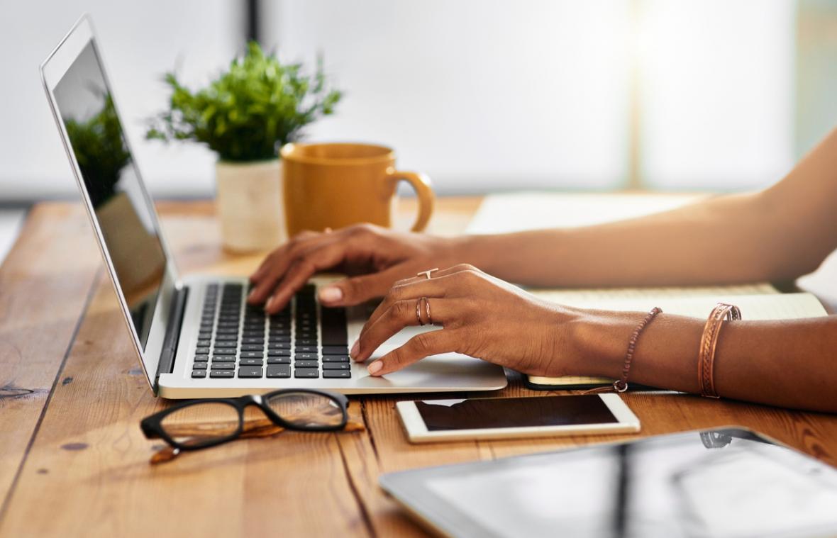 An image of a woman's arms typing on a laptop.